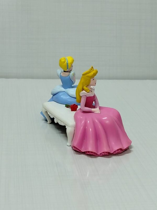 Cinderella figure and sleeping beauty sitting on the original bench